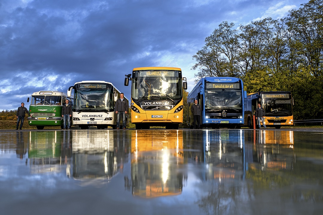 A képen a Groupama vezetéstechnikai tanpályán 5 busz látható autóbusz-vezetőikkel. Balról jobbra haladva: Ikarus 55 Lux zöld színű Faros retro autóbusz, új Credobus Econell 12, új Volvo 8900, új Mercedes-Benz eCitaro, új MAN Lions city. Az autóbuszok tükröződnek a tanpálya vizes aszfaltján.