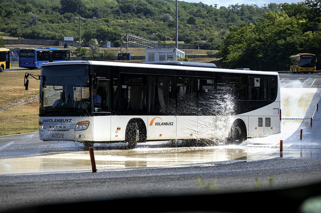 A képen egy autóbusz látható a Hungaroringon lévő csúszós utat szimuláló tanpályán. 