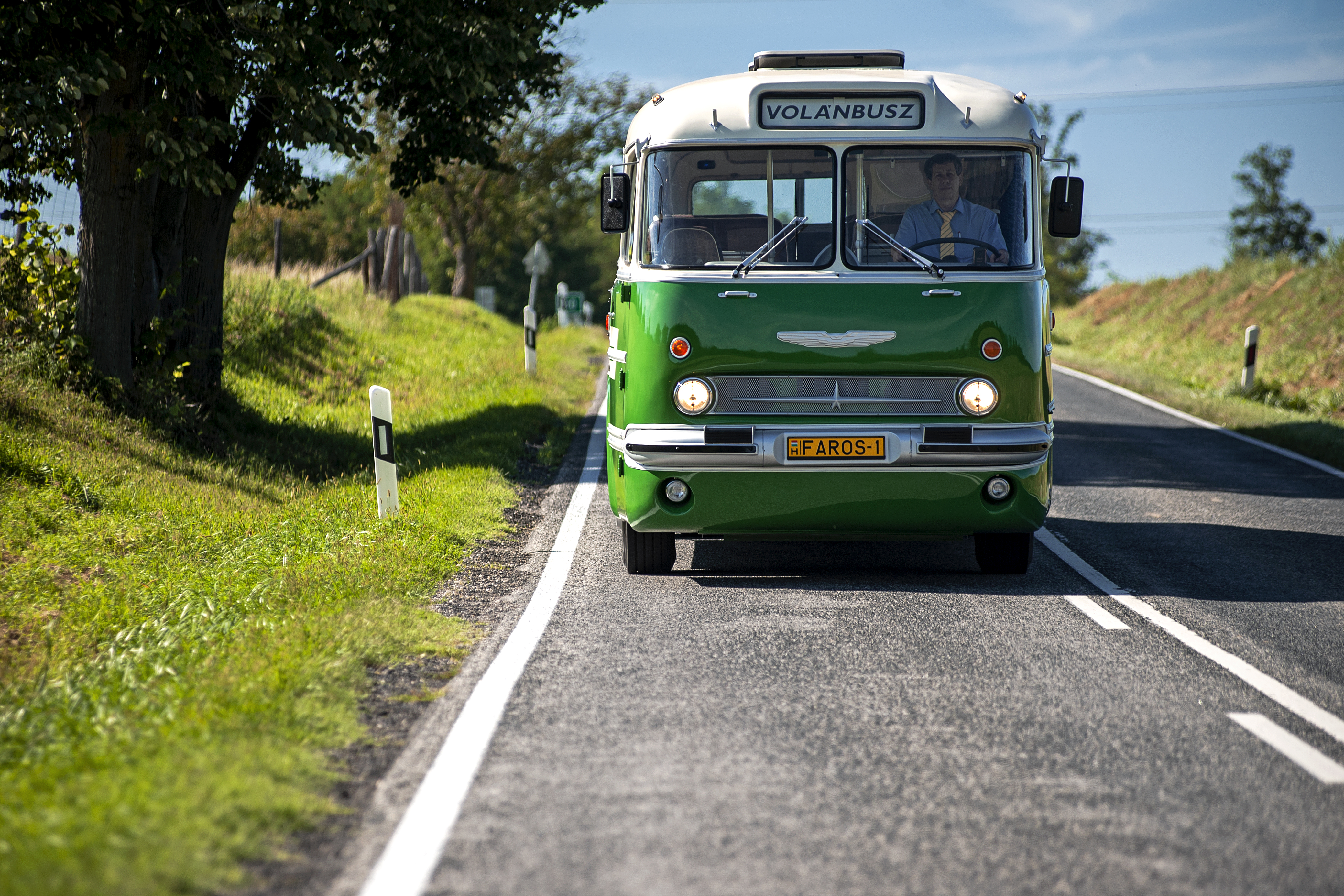 A képen egy retro, zöld színű ikarus 55 típusú autóbusz látható.