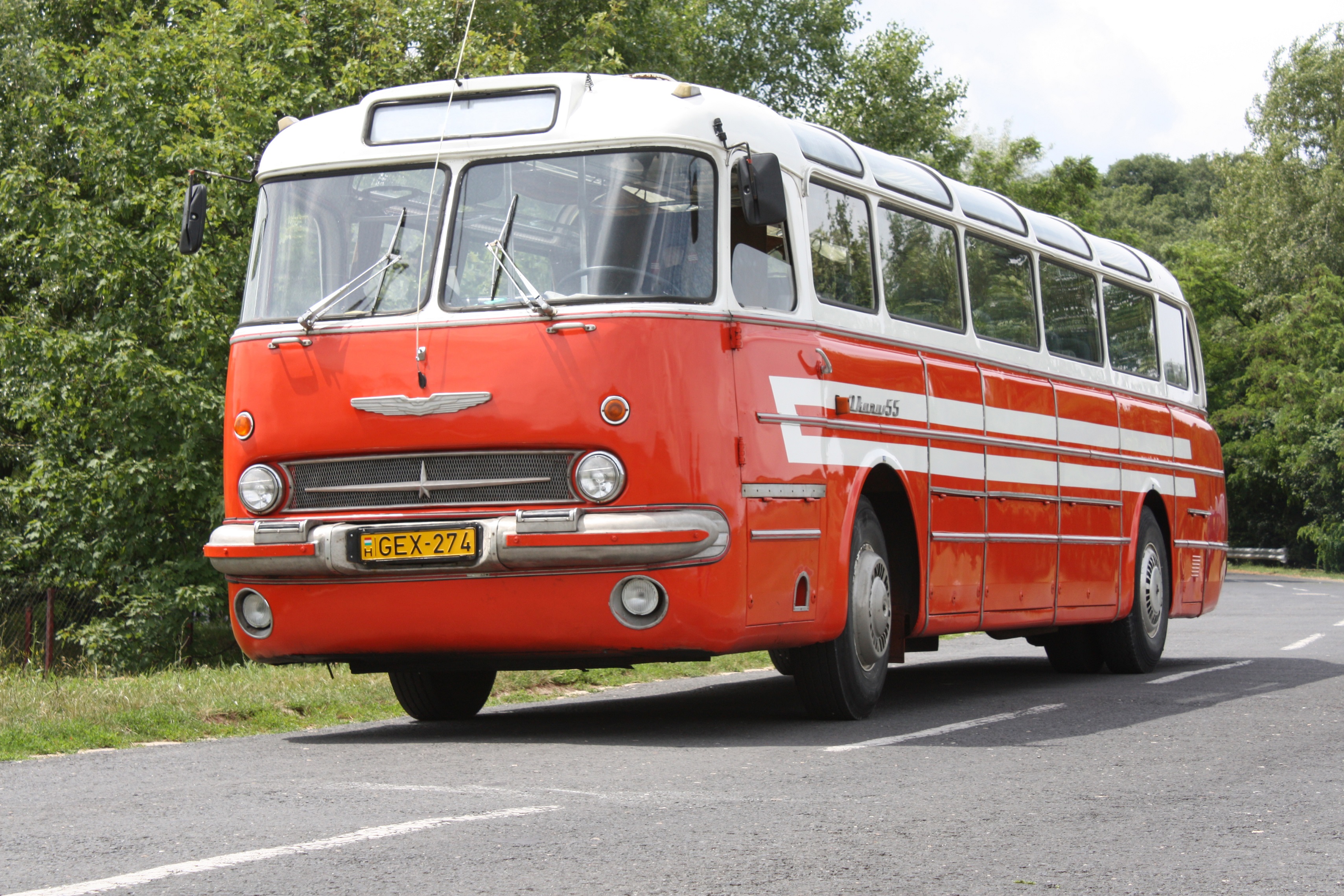 A képen egy retro, piros színű Ikarus 55 típusú autóbusz látható.