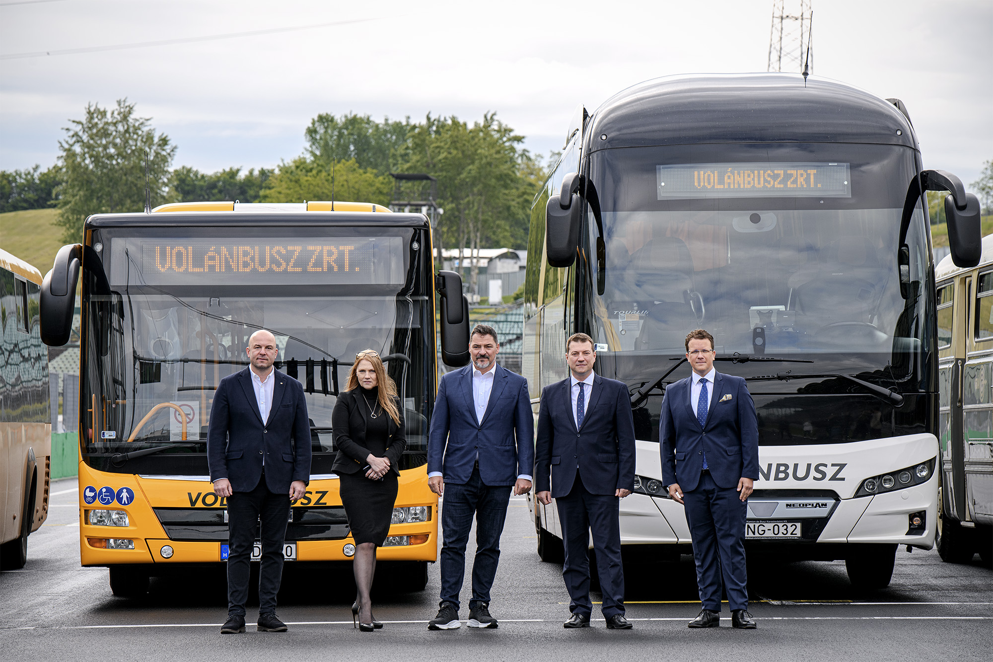A képen a sajtótájékoztató főszereplői láthatók az autóbuszok előtt állva.
