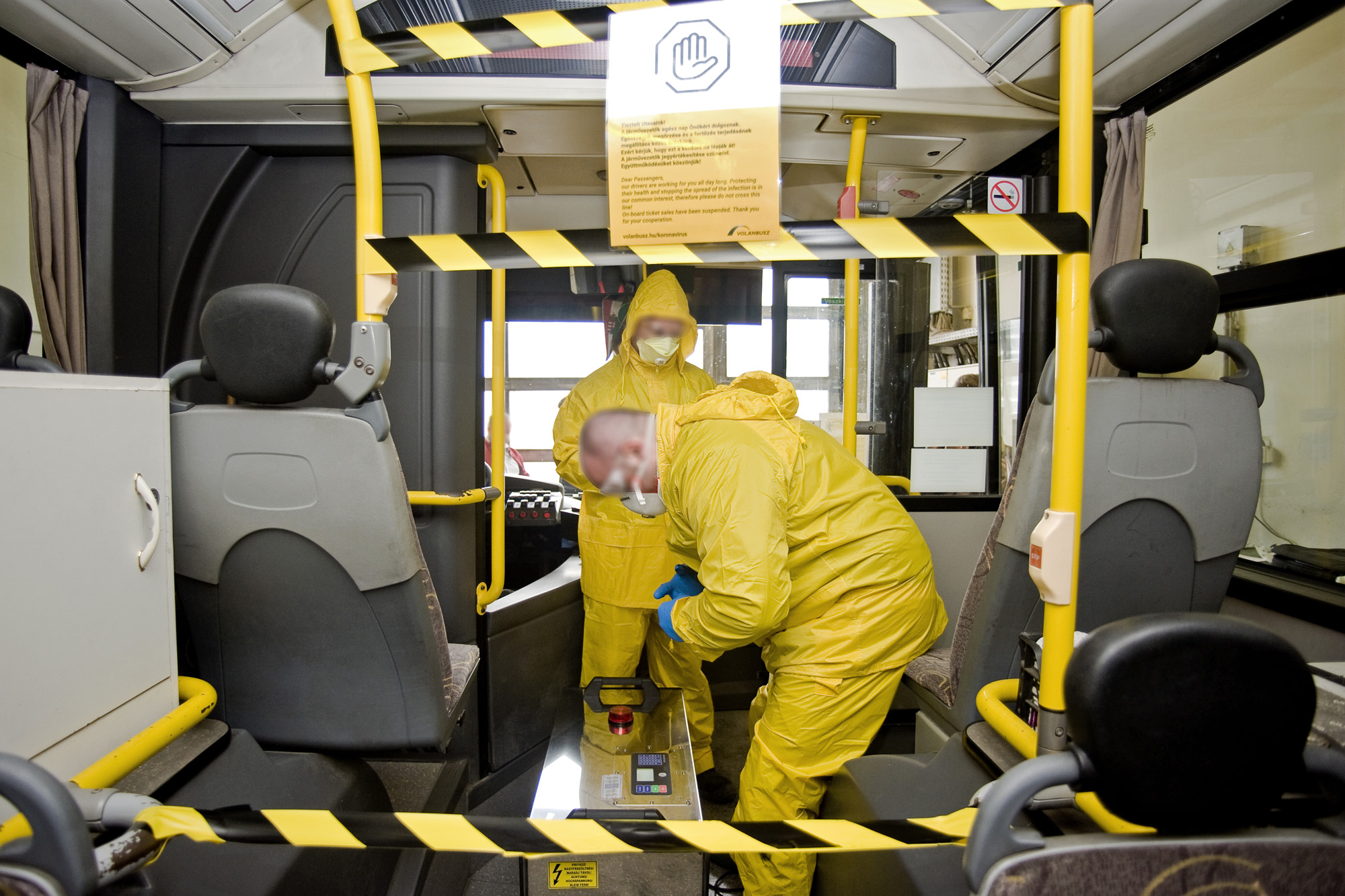 A képen védőruhás szakemberek fertőtlenítik az autóbuszt.